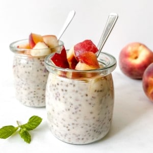 peach chia pudding in glass jars next to fresh peaches.