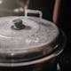 Detailed view of an old metal cooking pot with a black handle in a rustic kitchen setting.