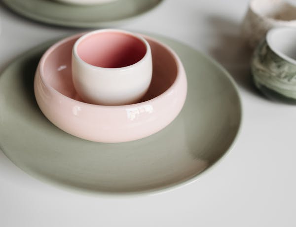 A close-up of colorful ceramic bowls and cups on a white table.